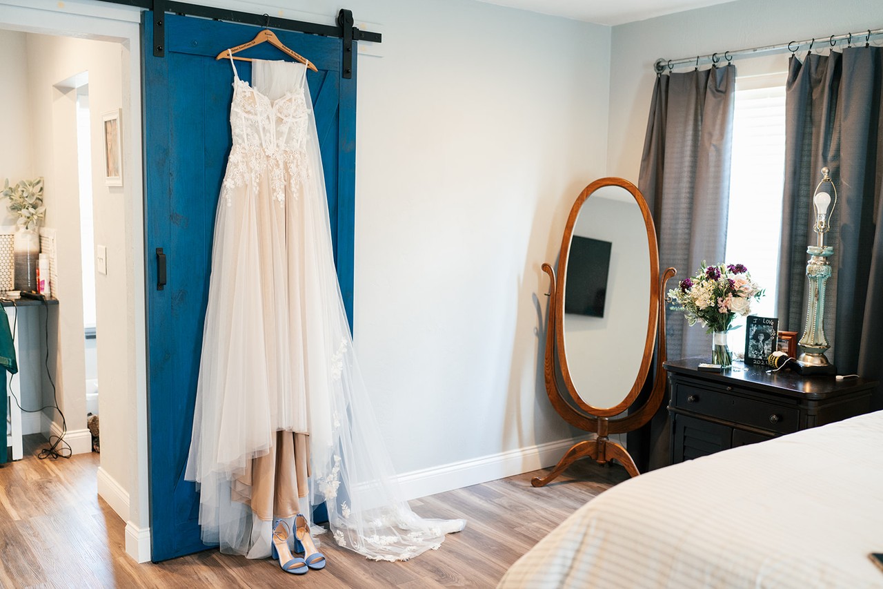 Danielle's lace gown hanging on a blue barn door in the getting-ready bedroom
