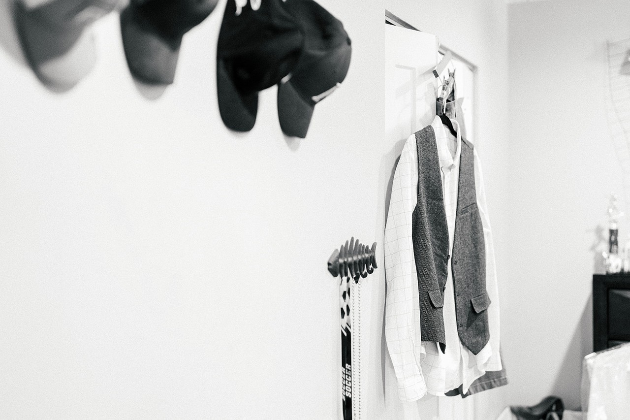 Groom's white shirt and grey vest hanging on the wall, black and white getting-ready detail
