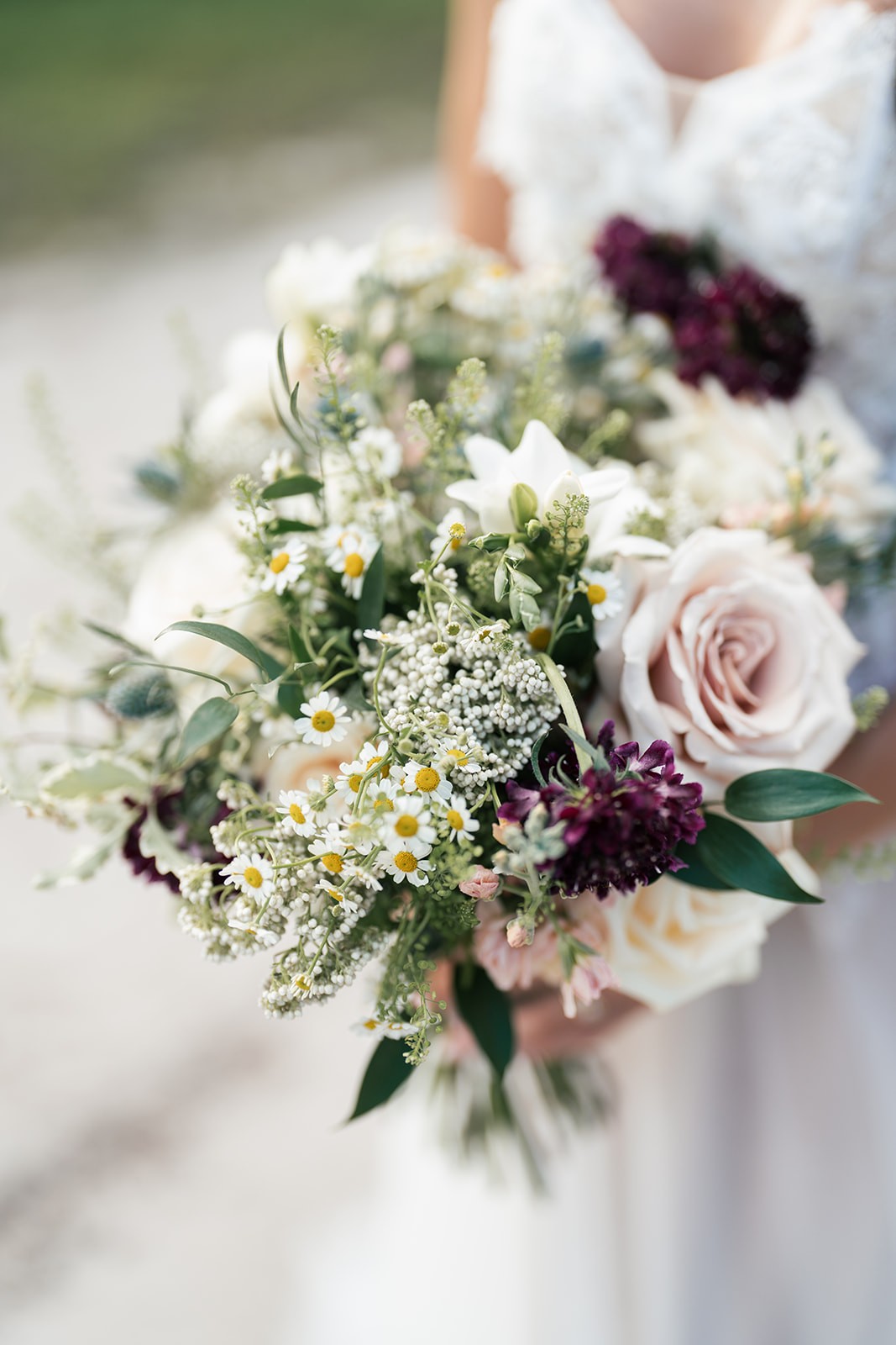 Danielle holds a lush bouquet of daisies, roses and deep plum blooms
