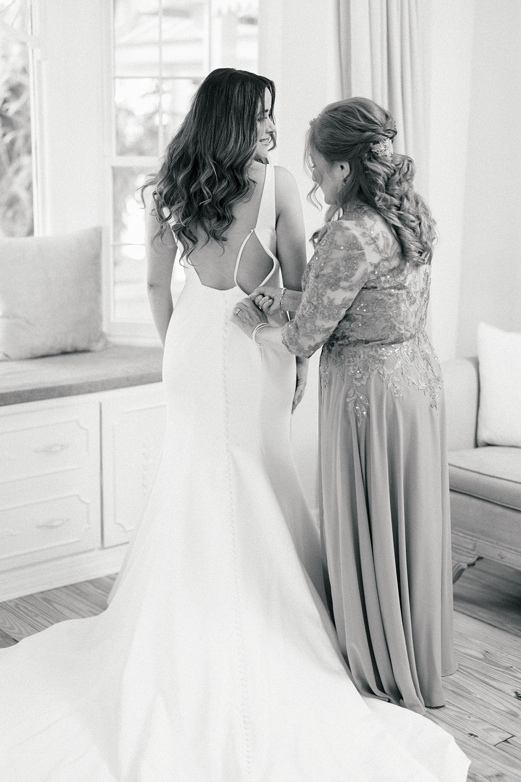 Mother helping fasten Chellsea into her open-back gown with long train