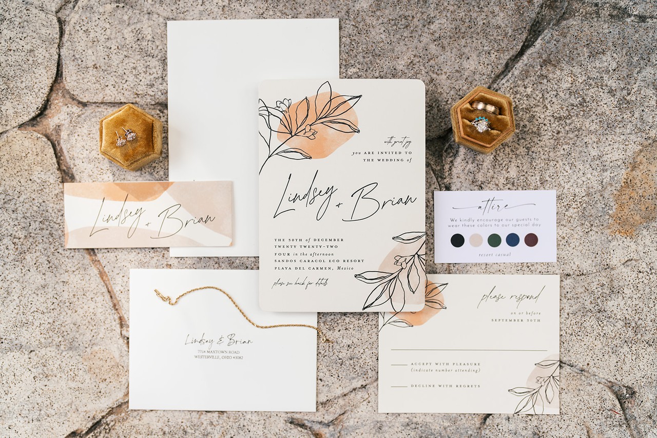 Lindsey and Brian invitation suite with floral details and ring boxes on stone