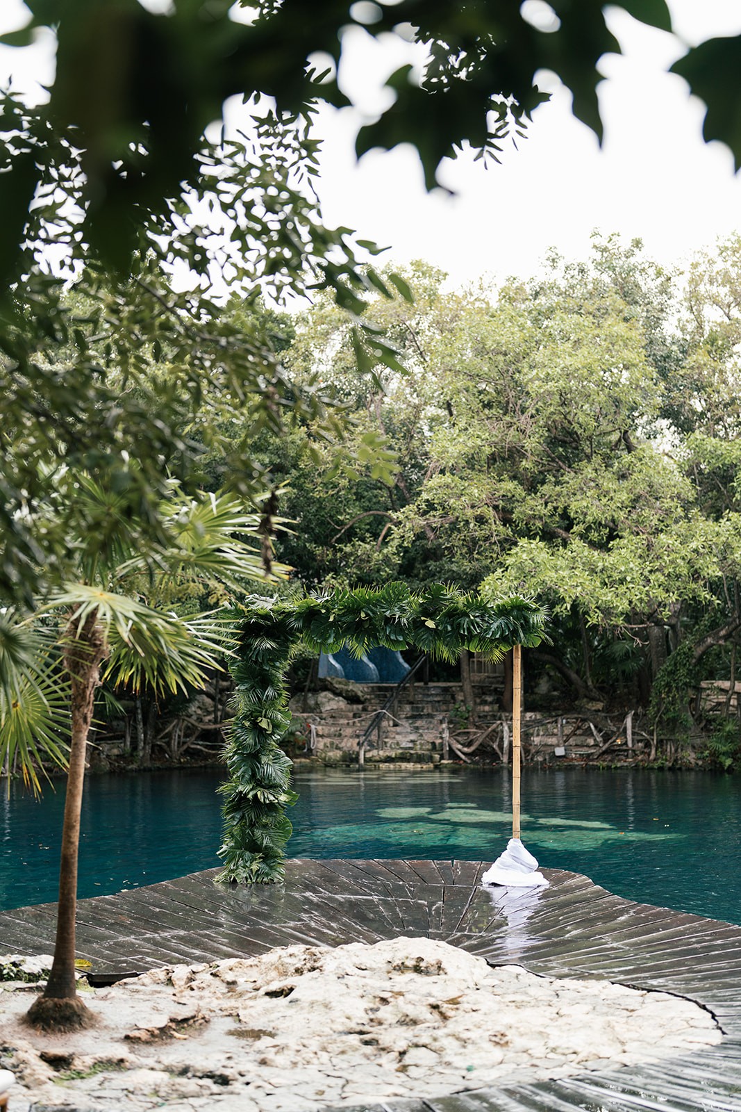 Tropical floral garland on a ceremony arch beside turquoise water and trees