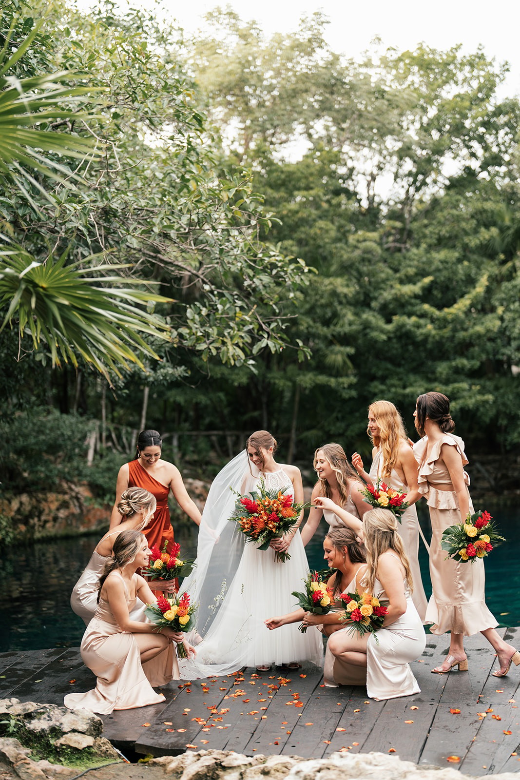 Bridesmaids gathered around Lindsey with bright bouquets on a dock by the water