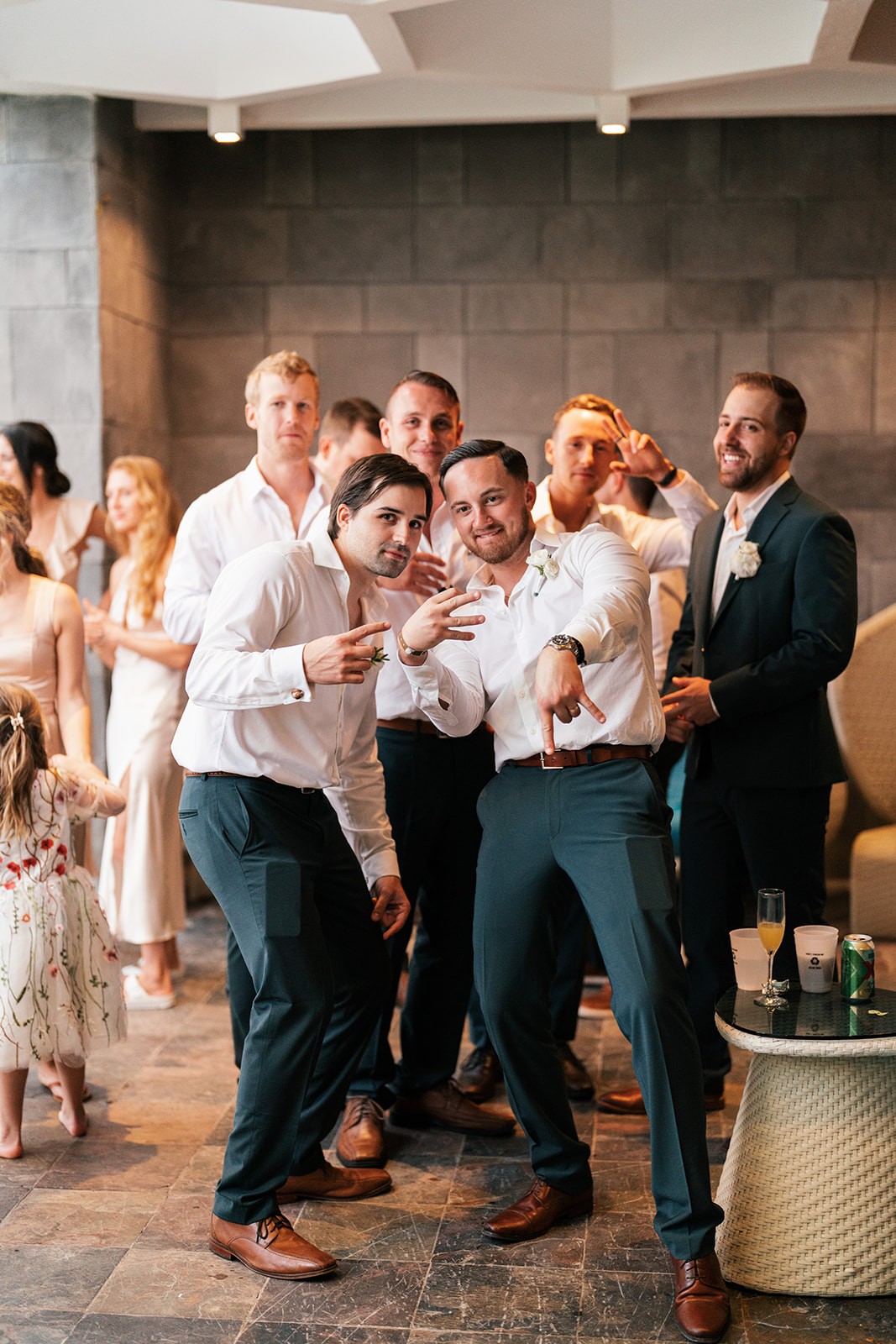 Groomsmen striking playful poses on the dance floor at the indoor reception