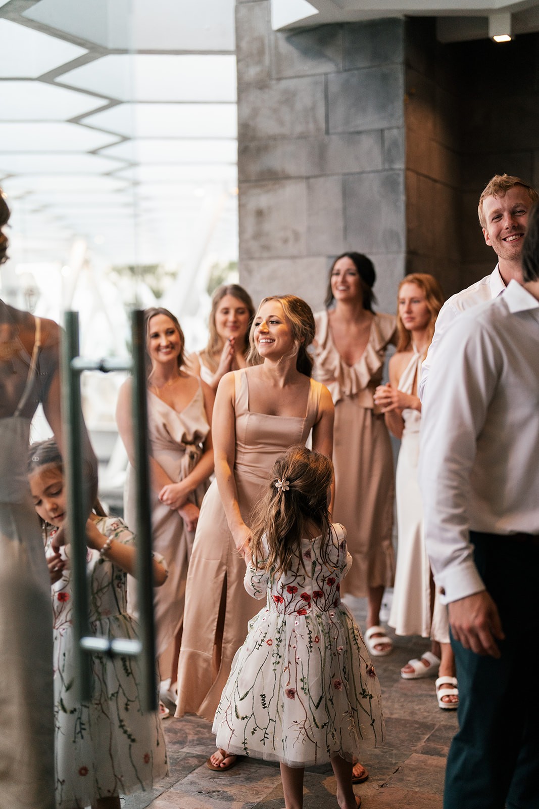 Lindsey laughing with bridesmaids and a flower girl during a joyful first look indoors