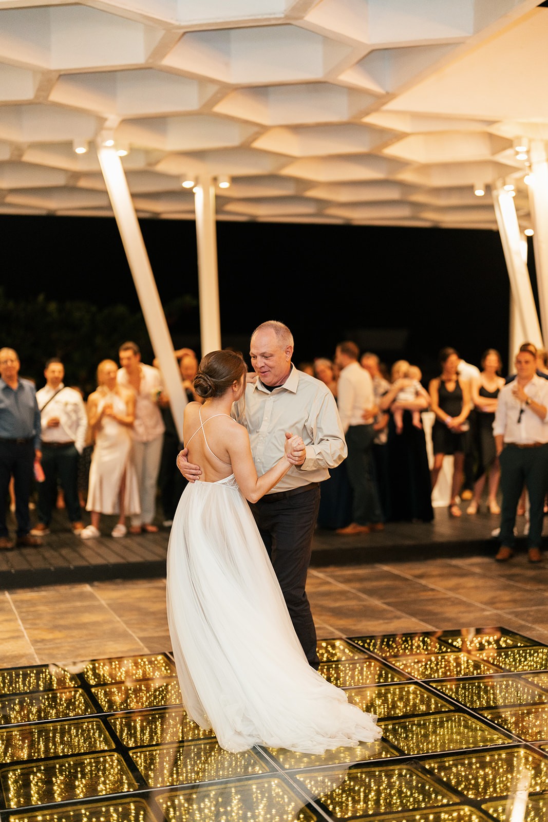 Lindsey dancing with an older man on a glowing lit dance floor as guests watch