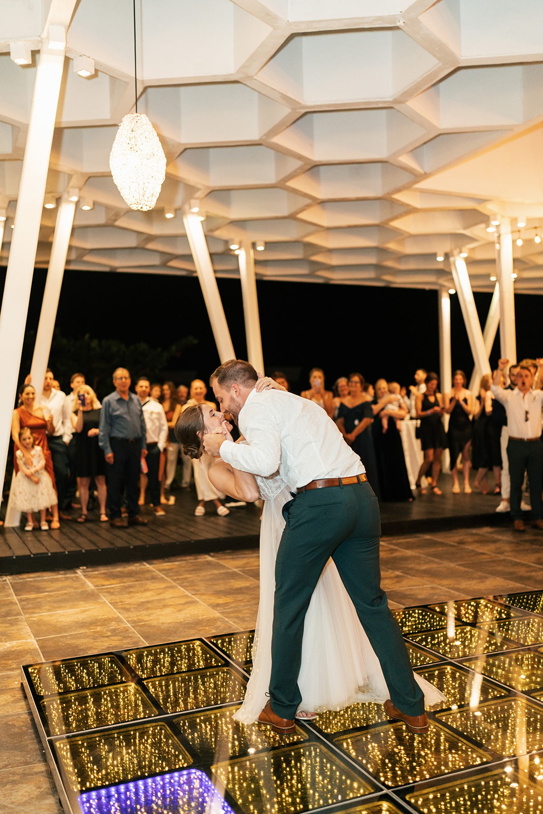 Brian dipping Lindsey for a kiss on the lit dance floor as guests cheer