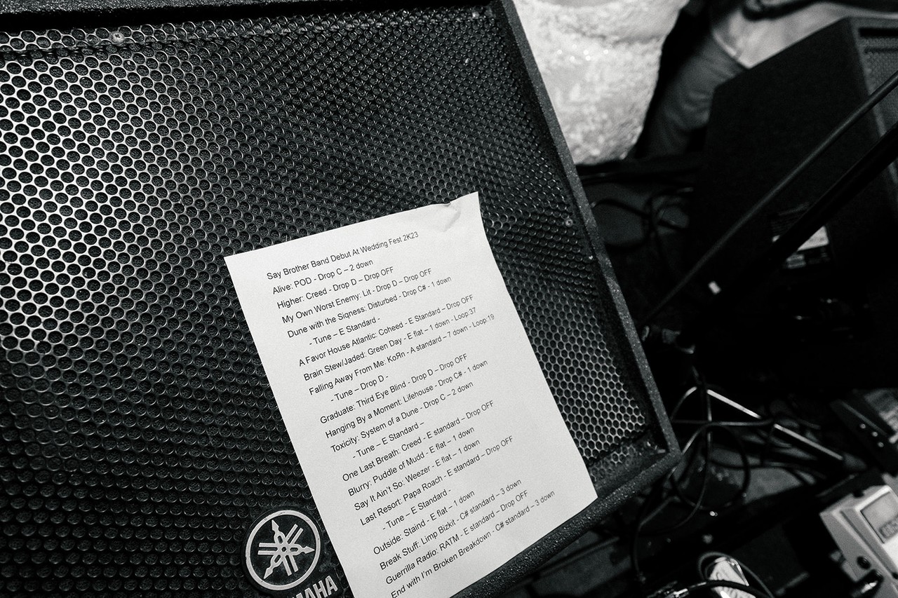 Reception band setlist taped to a stage monitor speaker amid cables and gear