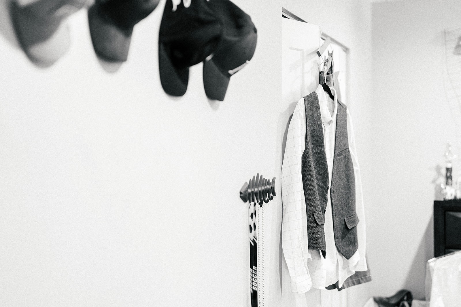 Groom's white shirt and grey vest hanging on the wall, black and white getting-ready detail