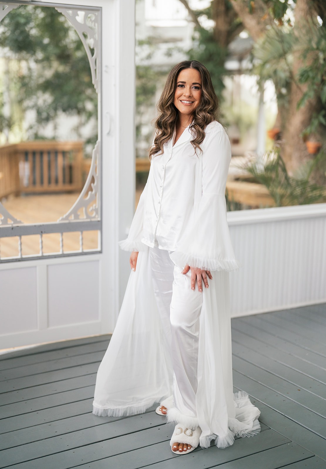 Chellsea smiling in a white bridal robe on a screened porch at Up the Creek Farms