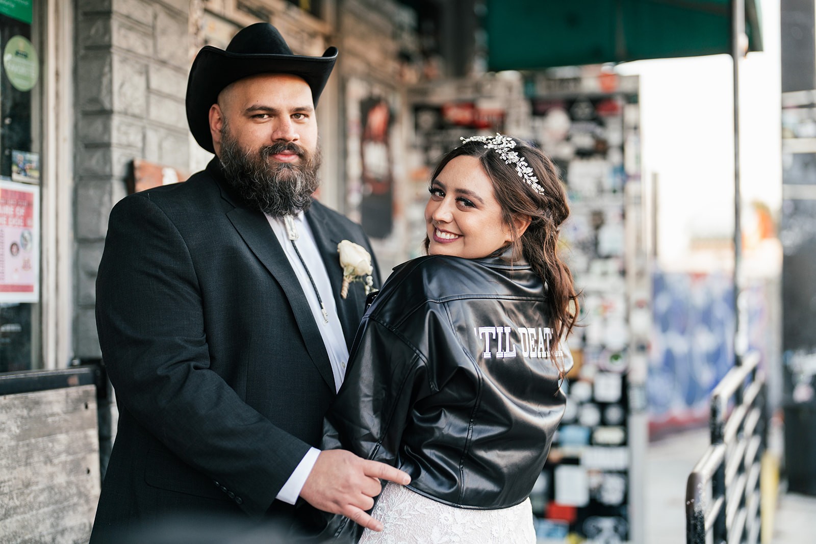 Sydney in a 'Til Death jacket and Manny in a cowboy hat posing outside a record shop