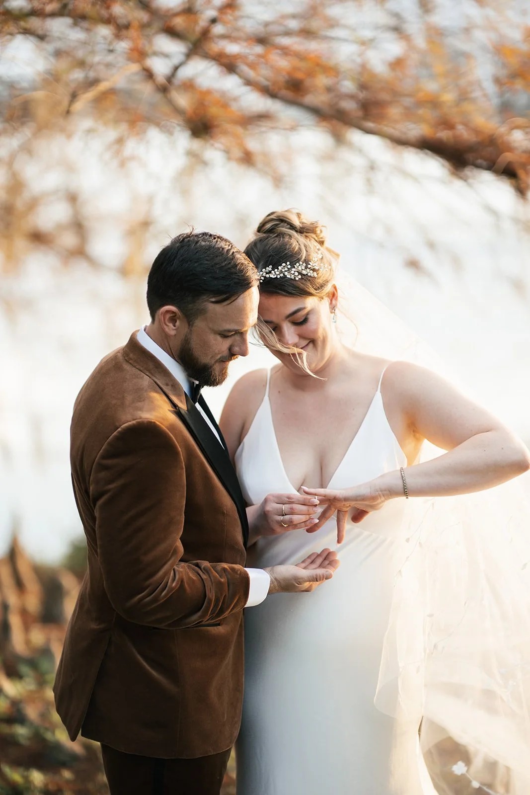 Groom slides a ring onto the bride's finger as she smiles during the ceremony