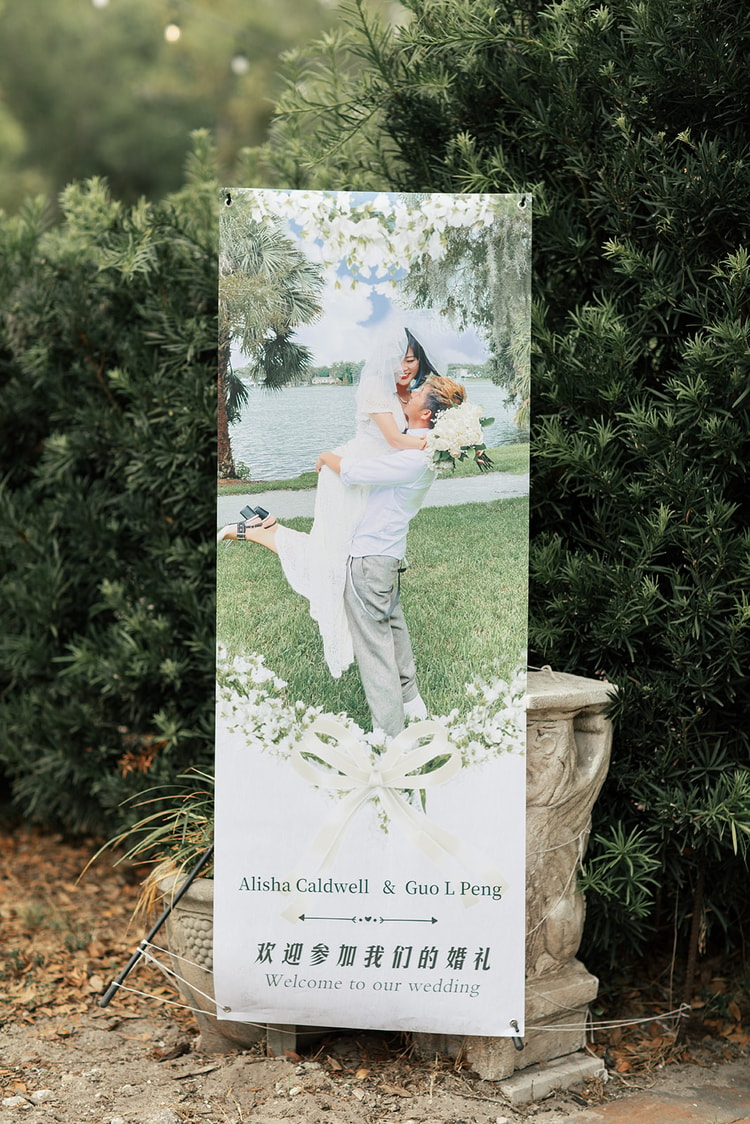 Bilingual wedding welcome banner featuring a couple portrait, Chinese characters, and the names Alisha Caldwell and Guo L Peng displayed against lush garden greenery.