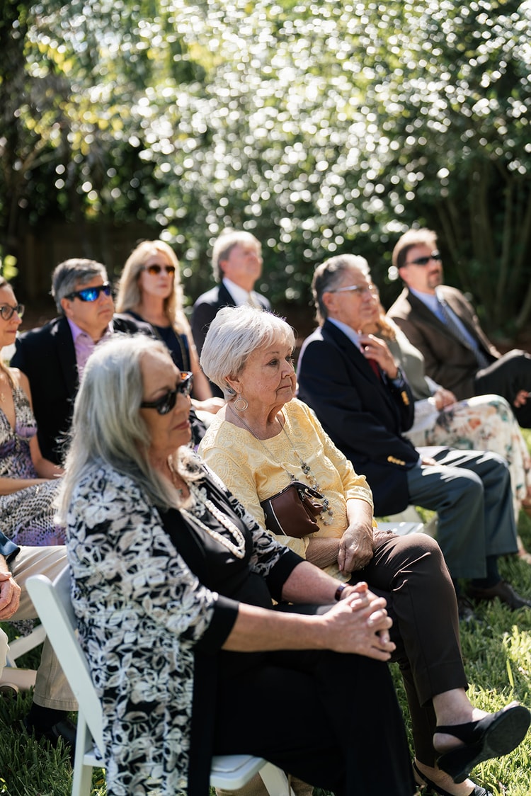 Guests seated in the front ceremony rows watching intently, including family members in the foreground.