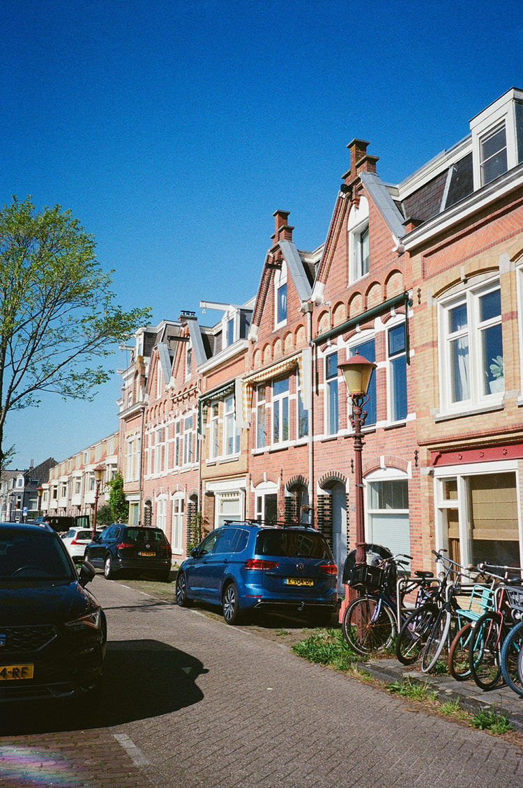 Classic Dutch row houses with peaked tile roofs against a clear blue sky, bicycles parked below.