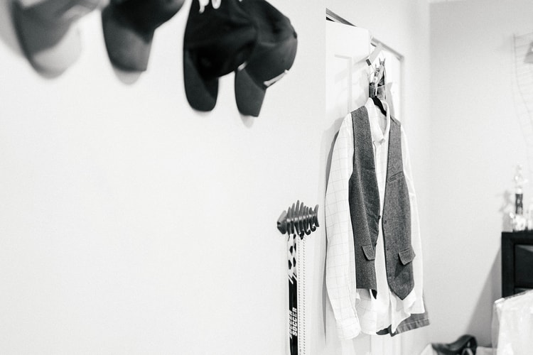Groom's white shirt and grey vest hanging on the wall, black and white getting-ready detail