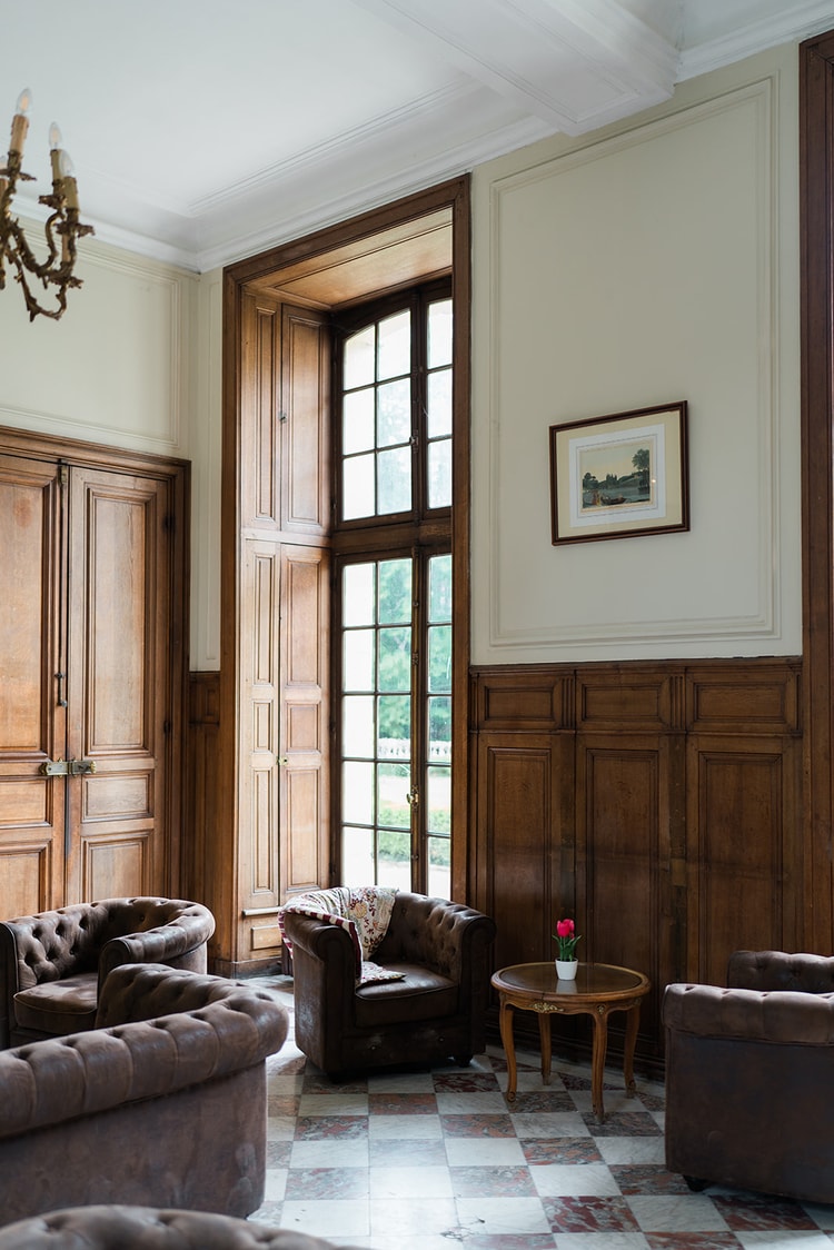 Crimson velvet chairs and white-clothed tables in the dark panelled dining room of Domaine du Château d'Ermenonville