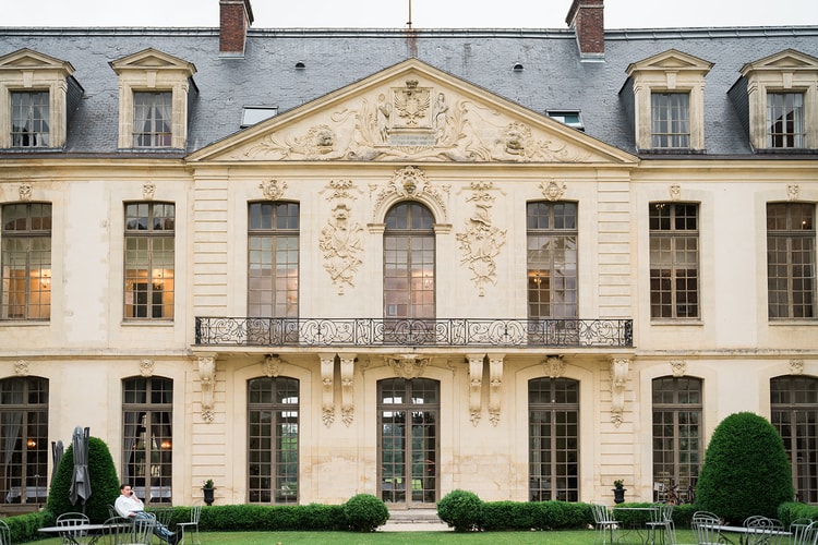 The full symmetrical front of Domaine du Château d'Ermenonville from its stone bridge, balustrades flanking the gravel court over the moat