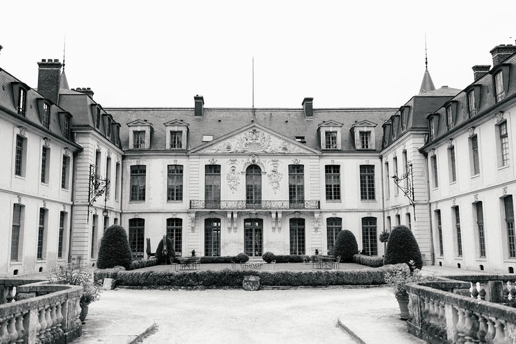 Symmetrical courtyard facade of Domaine du Chateau d'Ermenonville in black and white, framed by stone balustrades and manicured hedges