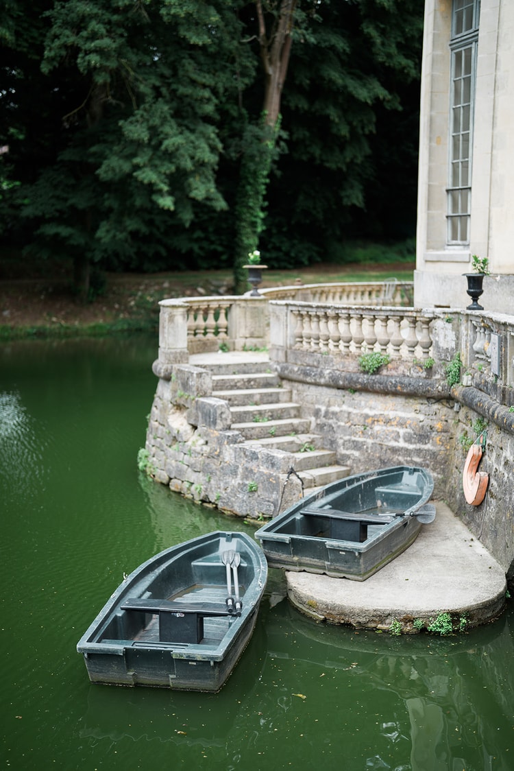 Rowboats waiting at the stone steps of the moat at Domaine du Chateau d'Ermenonville, green water lapping the old walls