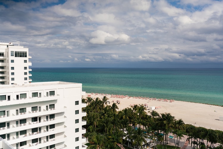 Aerial view of a white beachfront hotel flanked by palm trees and a wide sandy beach with turquoise water, wedding photography