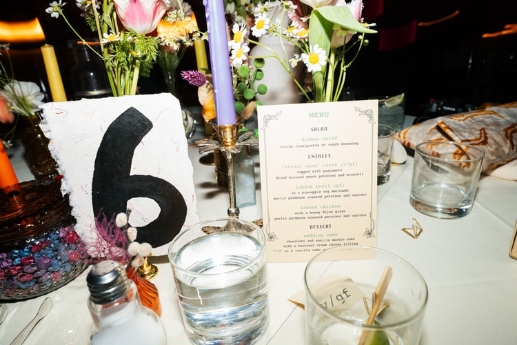 Reception table setting detail with a floral centerpiece, menu card, table number, and glassware