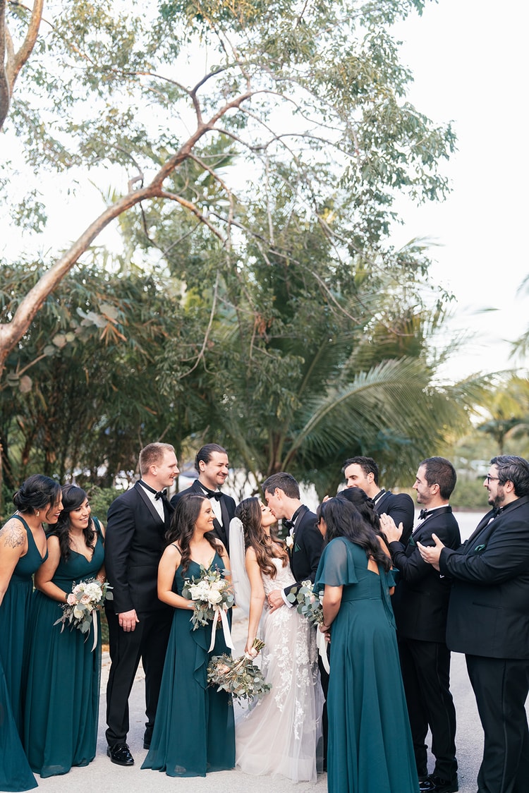Groom kisses the bride on the forehead during couple portraits, her expression content and glowing in warm afternoon light.