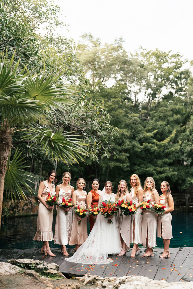 Bride posing with her family, the group arranged together with jungle foliage framing them naturally