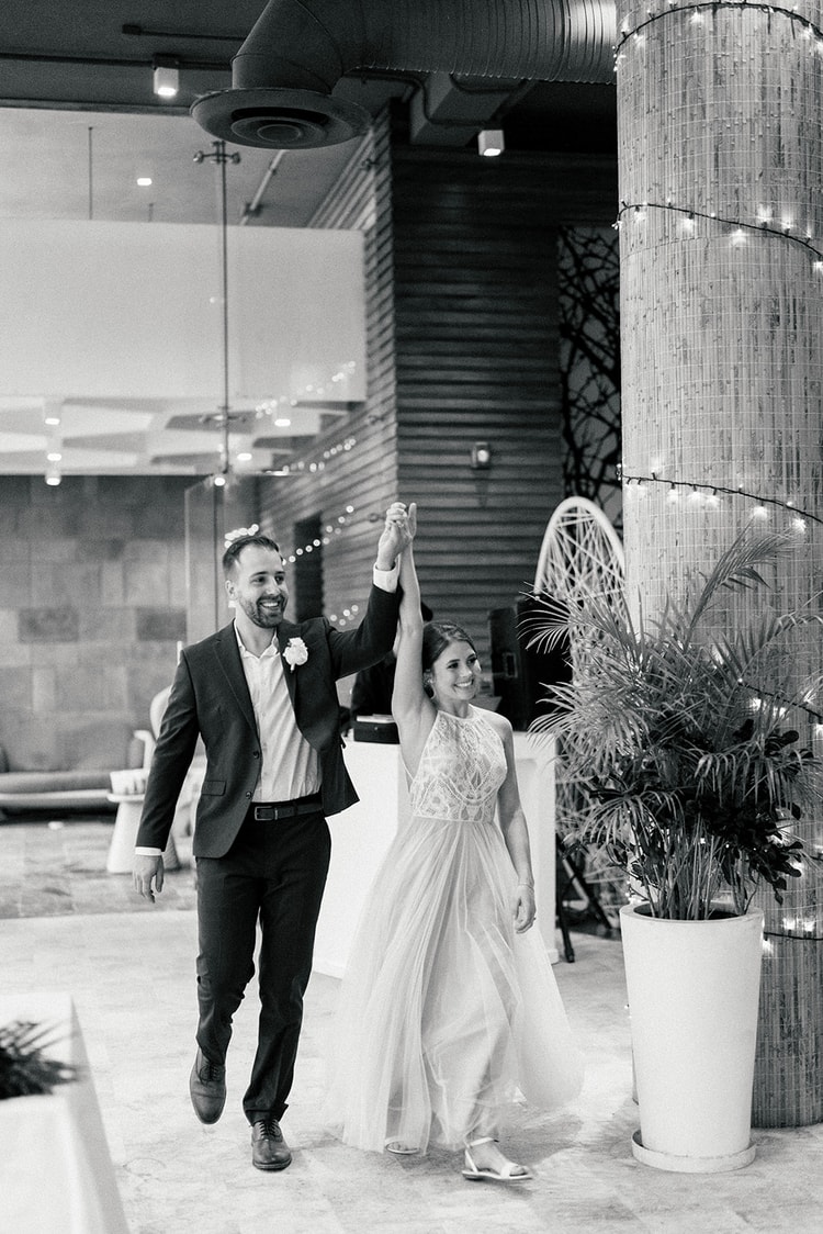Bride and groom make their grand entrance into the reception hall raising their joined hands