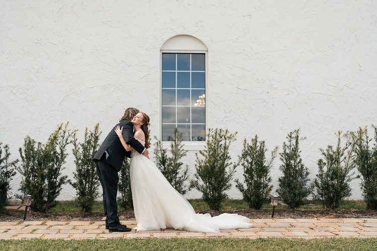 Bride and her father embracing in a first look on the venue patio, her tulle train spread across the stone path