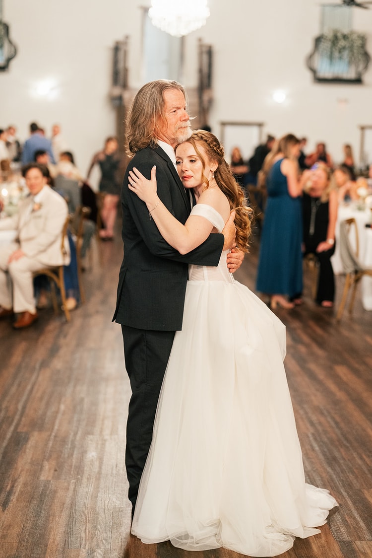 Bride embraces her father on the dance floor during their father-daughter dance at an Orlando reception hall.