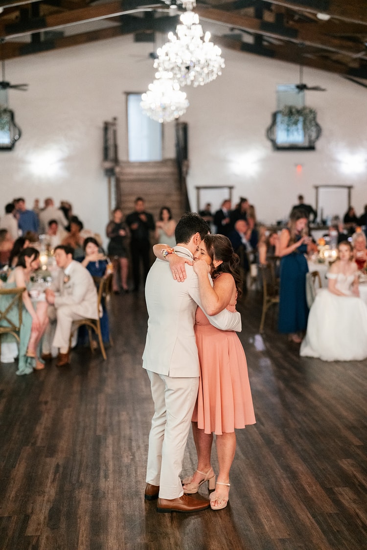 Groom shares an emotional embrace with his mother on the dance floor during the mother-son dance at the reception.