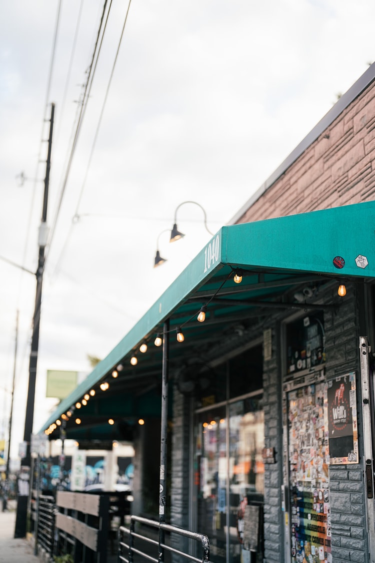 Street-level exterior of a brick music venue with a teal awning and string lights strung along its facade, setting the scene for the reception